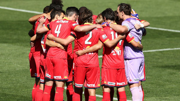 Adelaide United players form a huddle before kick-off at Coopers Stadium.